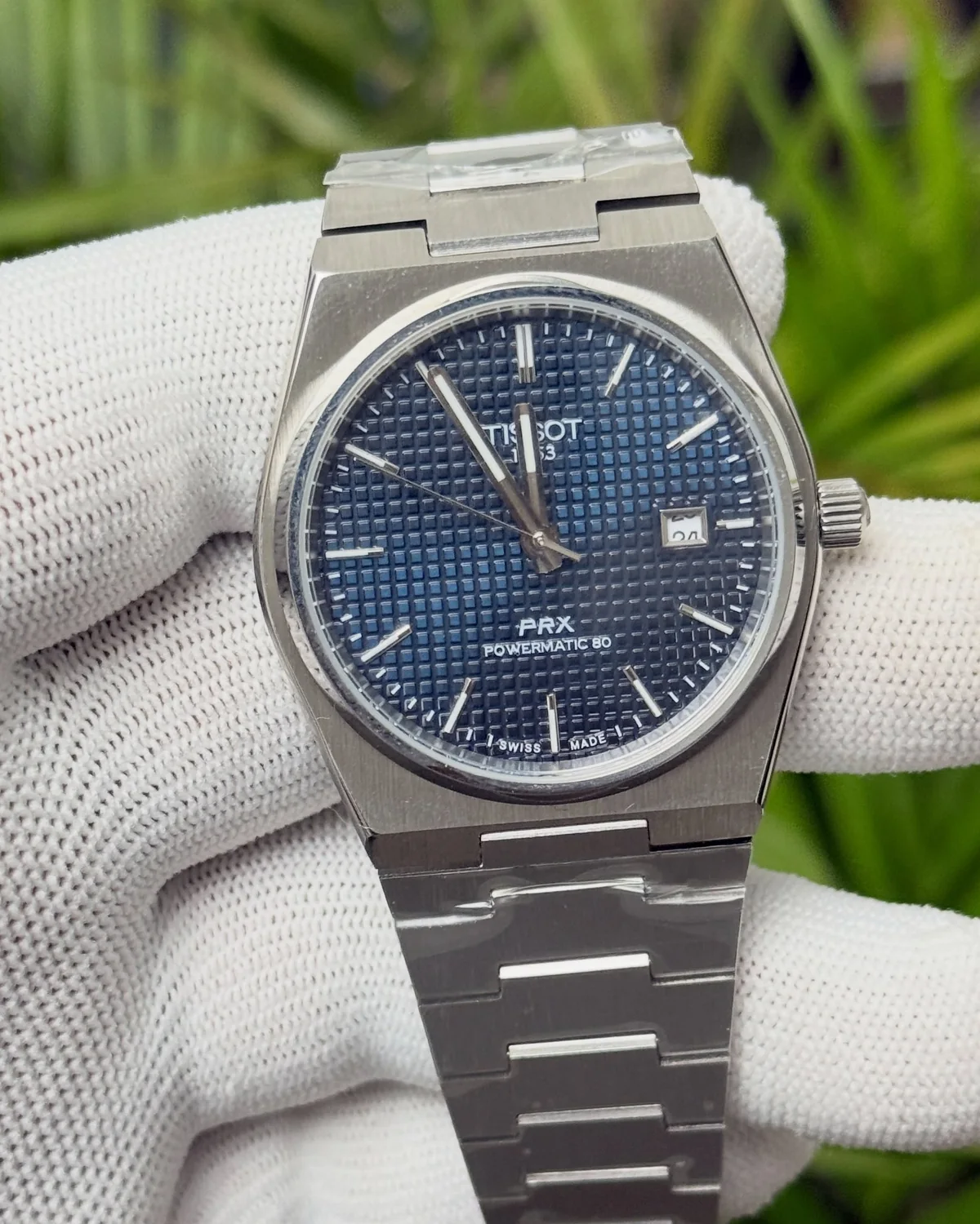Blue-dial round-case watch with an integrated bracelet, photographed by Ocean Gem & Jewel